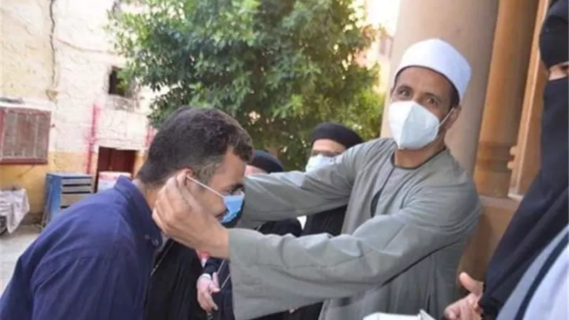 بالصور... إمام مسجد ومنتقبات يوزعون كمامات ومطهرات على الاقباط